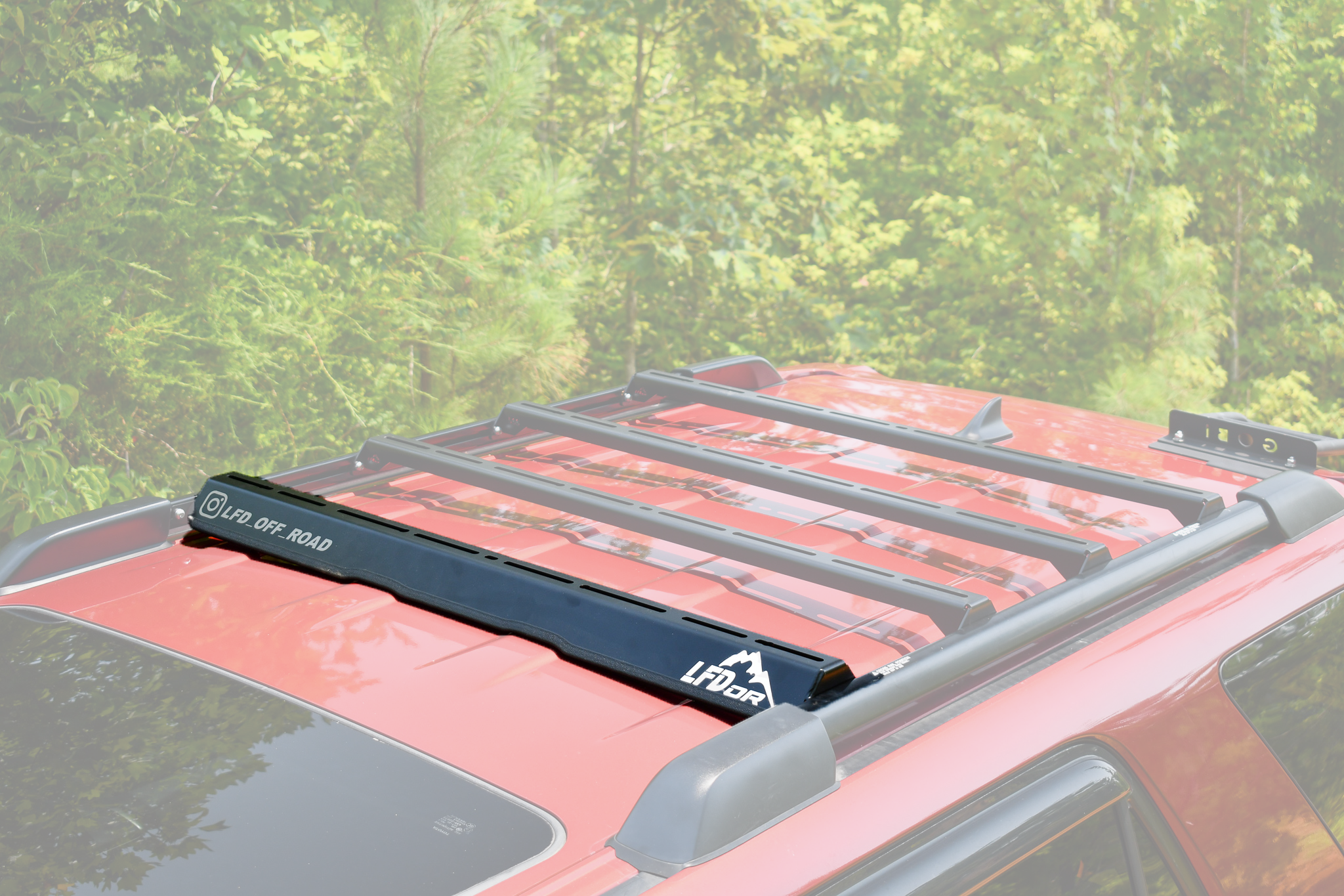 A black integrated wind fairing ruggedized crossbar mounted on the roof of a vehicle.