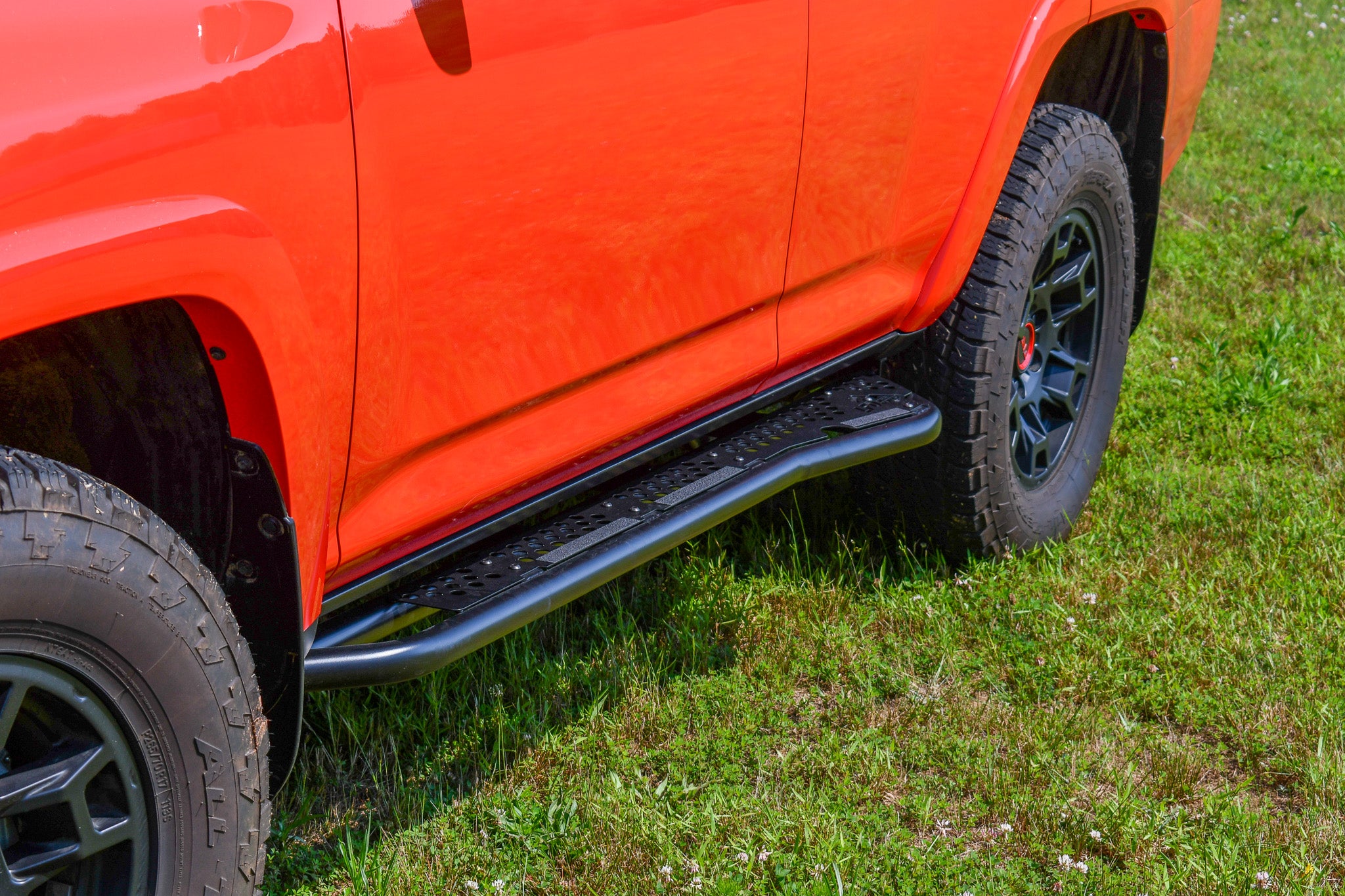 Black bolt on sliders attached to the lower side of an orange vehicle, designed for off road use.