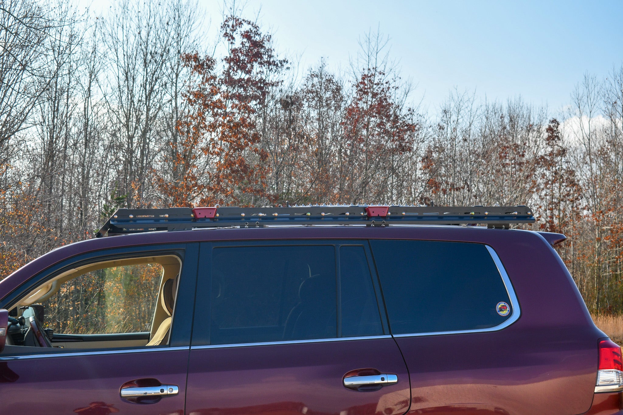 A set of full length stainless steel side rails installed on the roof of a vehicle, with mounting points and crossbar connections visible.