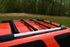 Ruggedized Aluminum Extrusion Crossbars mounted on the roof of an orange 4Runner SUV.