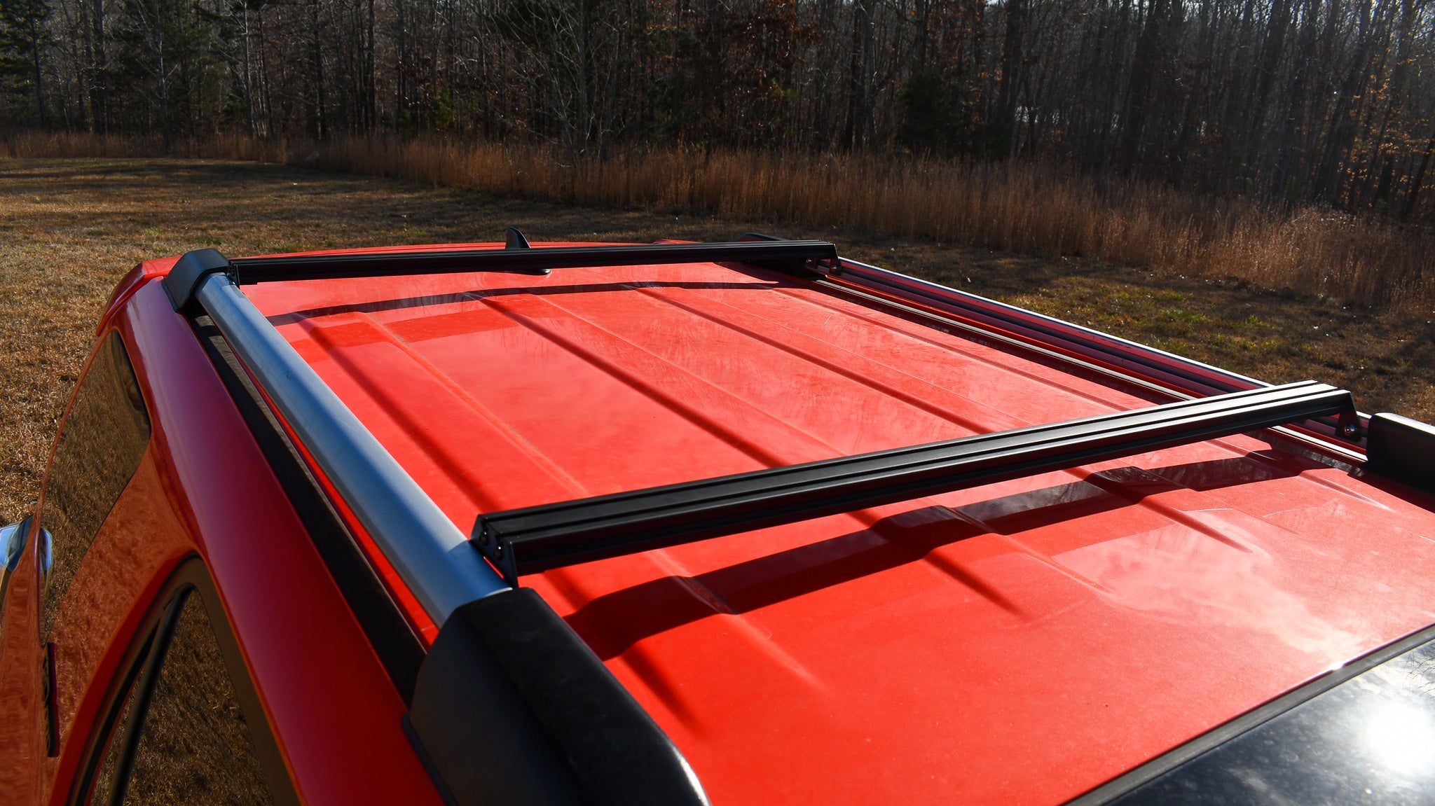 Ruggedized Aluminum Extrusion Crossbar installed on the roof of a red 4Runner SUV.