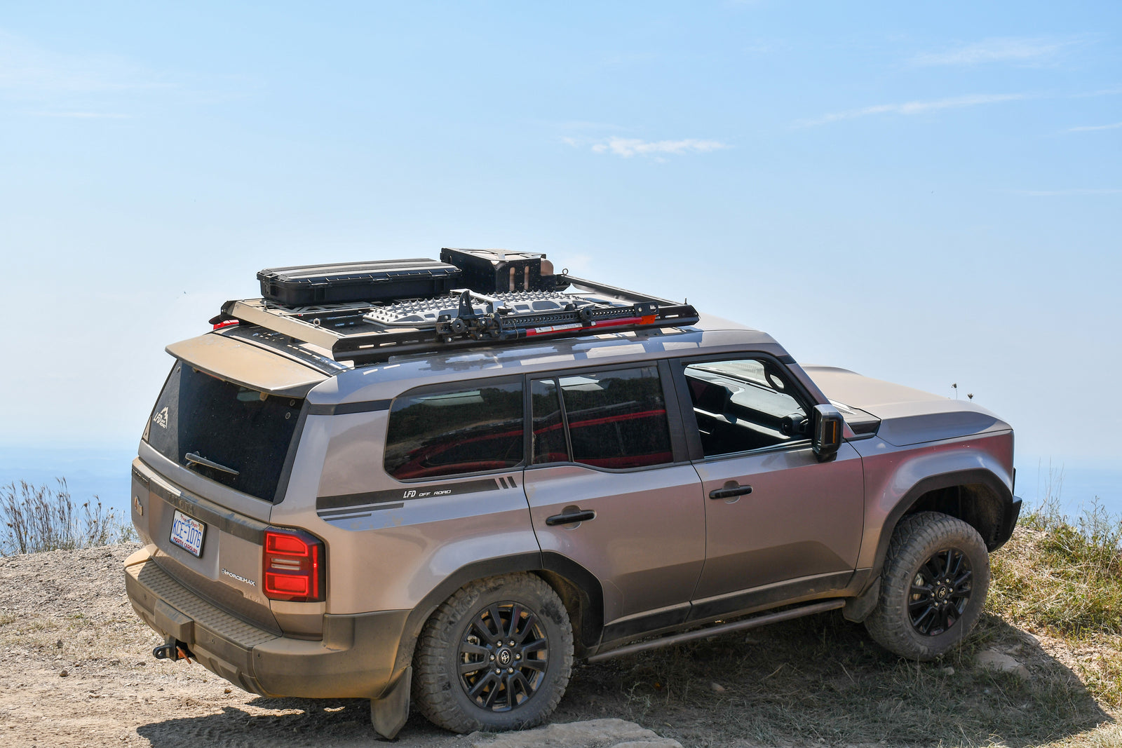 A silver 2024+ Land Cruiser with a black full length roof rack installed on top.