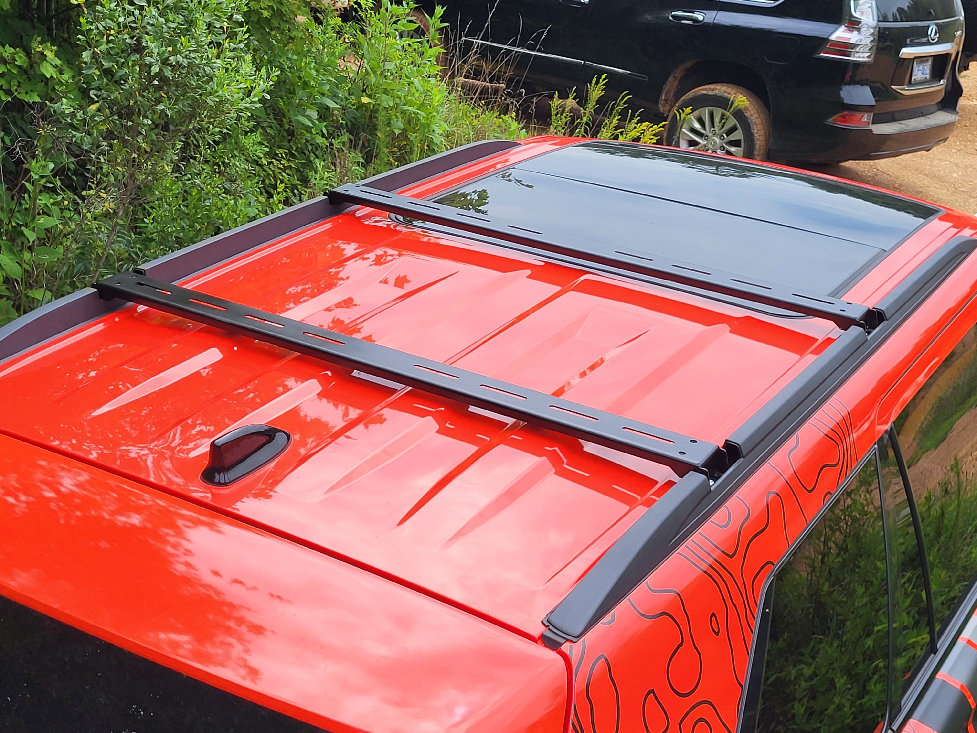Black powder-coated steel crossbars mounted on the roof of a red Sequoia vehicle.