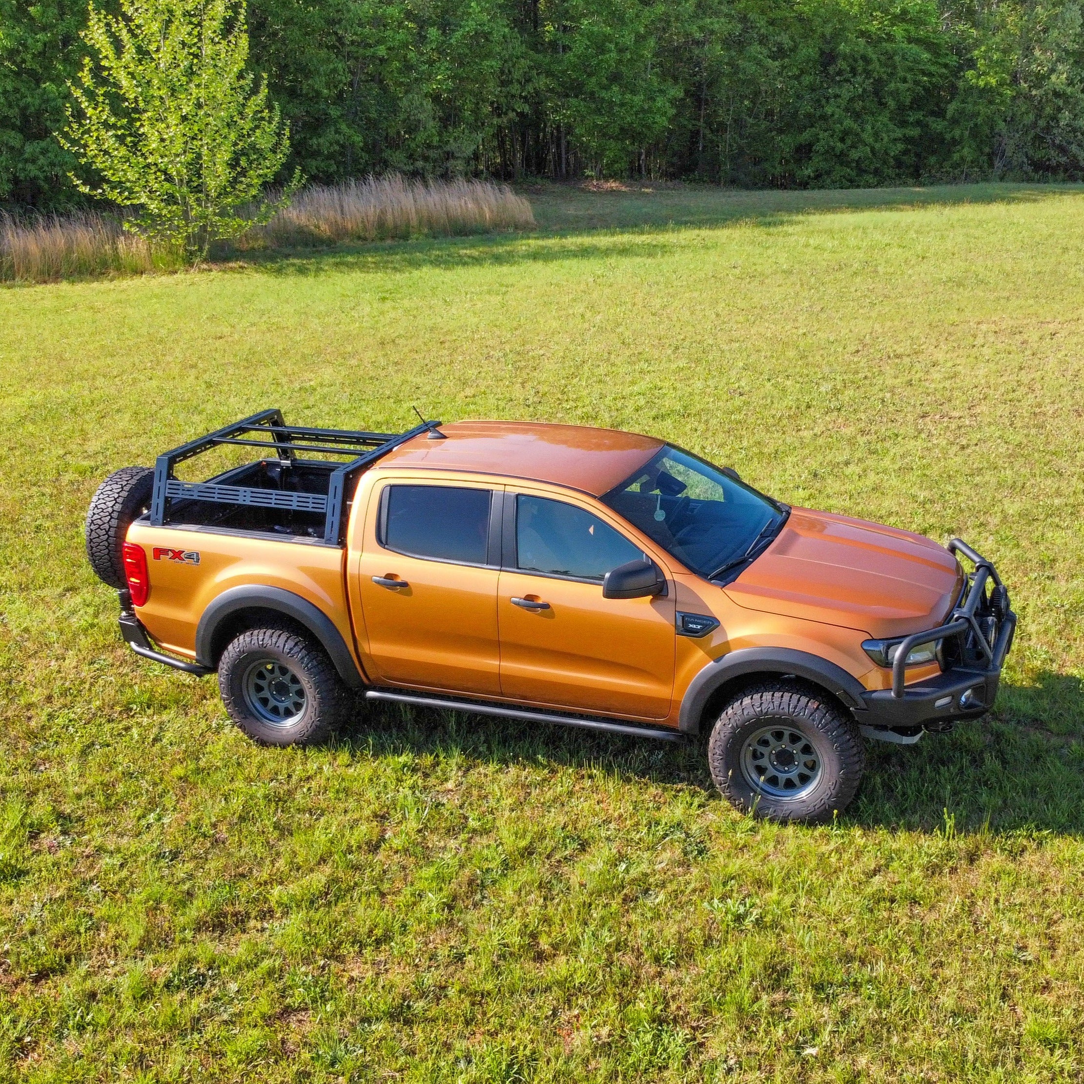 An orange Ford Ranger pickup truck with a black bed rack system installed on the back.
