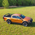 An orange Ford Ranger pickup truck with a black bed rack system installed on the back.