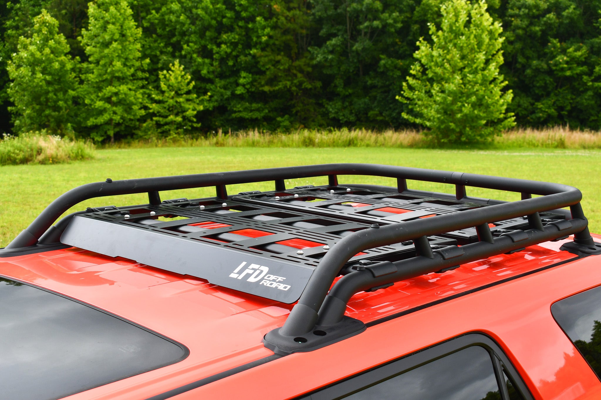 Aluminum cargo platform attached to a vehicle roof rack, designed for carrying recovery gear and other accessories, pictured on an orange vehicle.