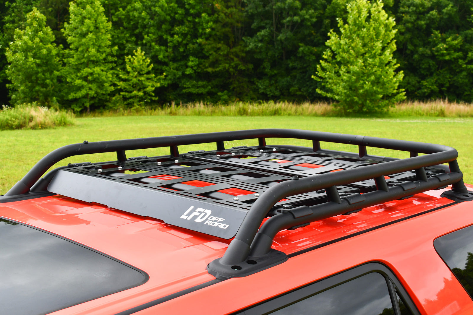 Aluminum cargo platform attached to a vehicle roof rack, designed for carrying recovery gear and other accessories, pictured on an orange vehicle.
