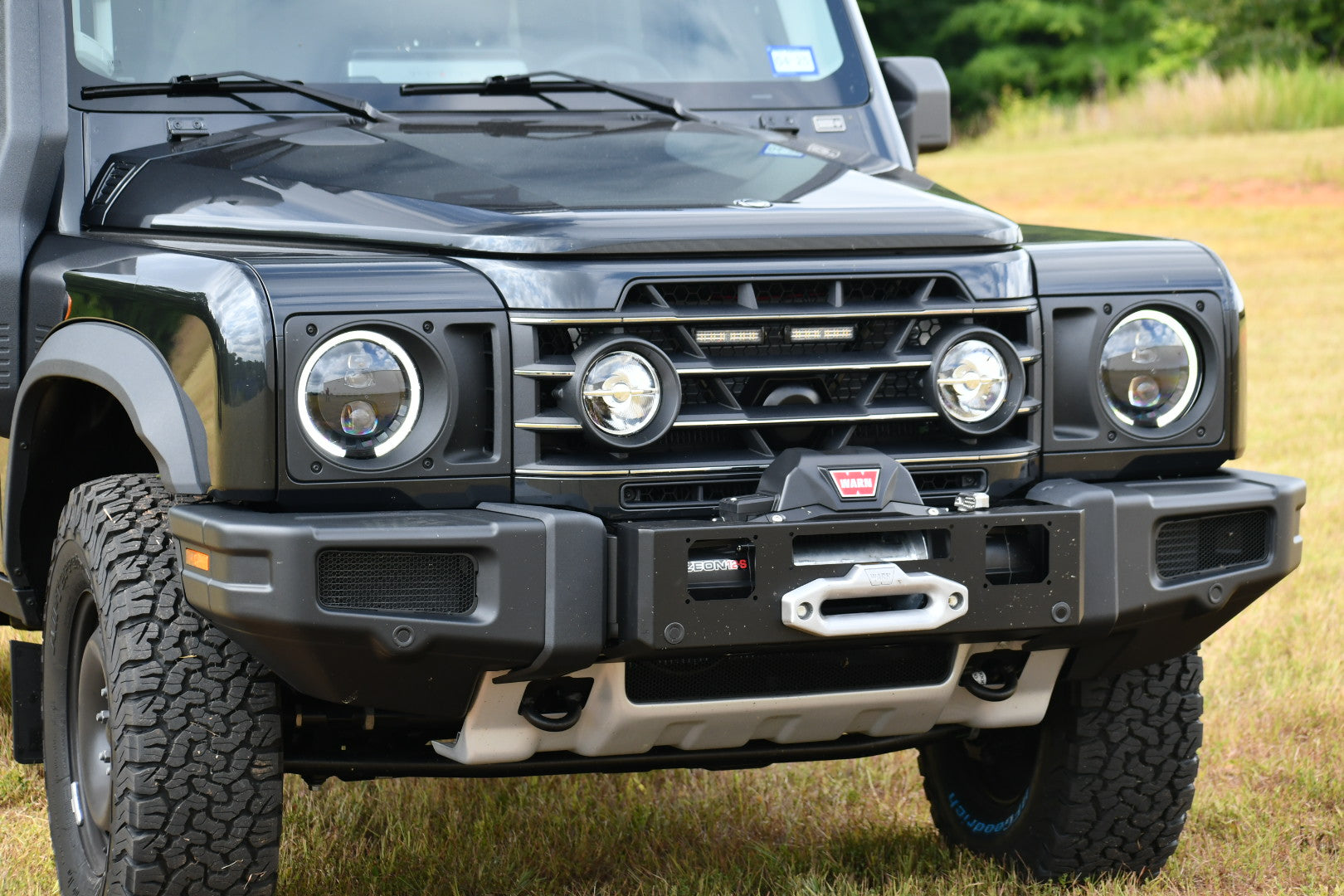 Front view of a black Ineos Grenadier vehicle featuring a center winch bumper.