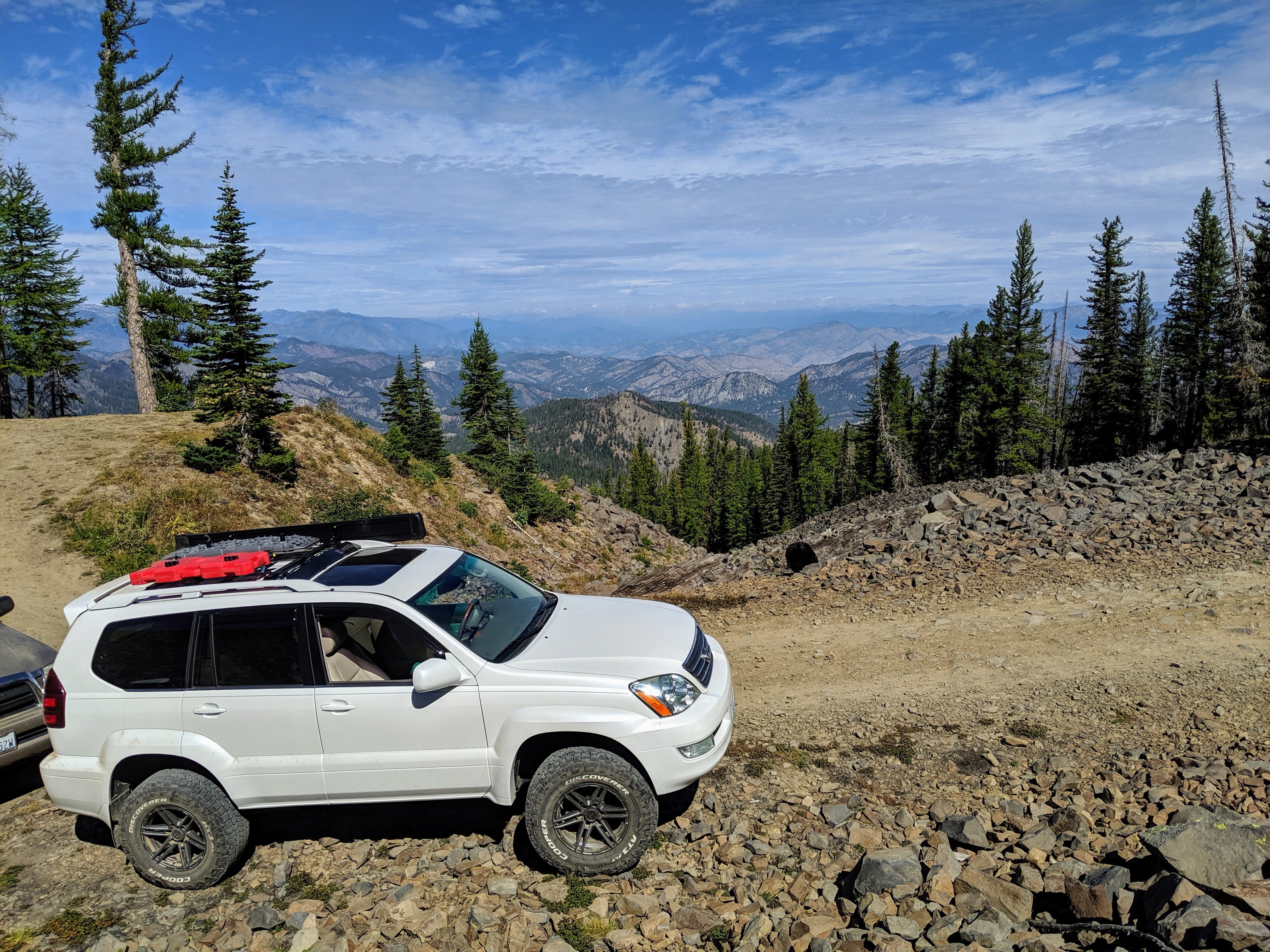 A white SUV with roof rails installed in a mountainous terrain