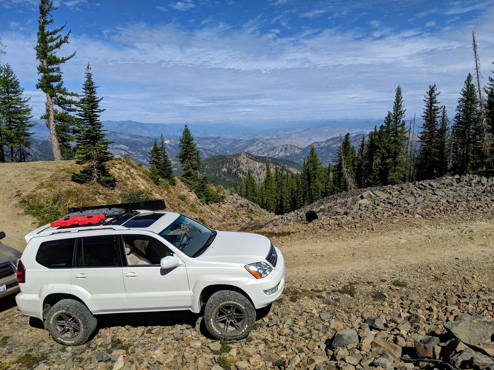 A white SUV with roof rails installed in a mountainous terrain