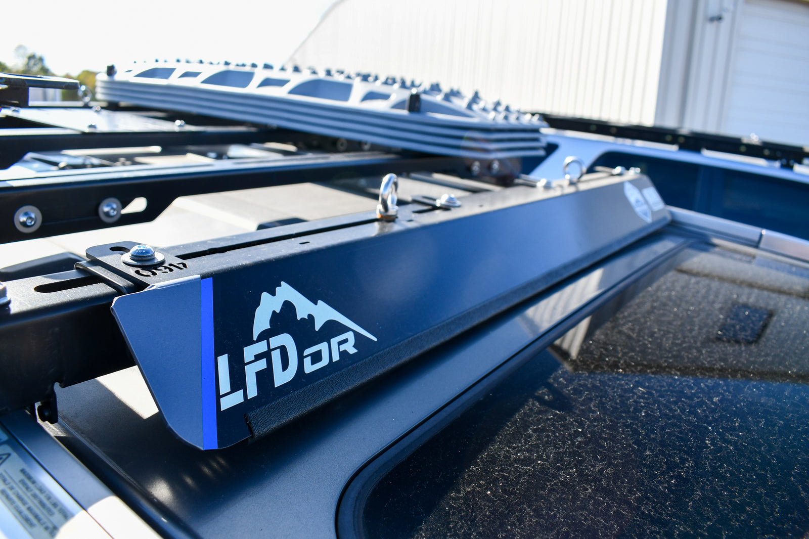 A blue bolt on wind fairing mounted on a vehicle roof rack, with the LFD logo visible.