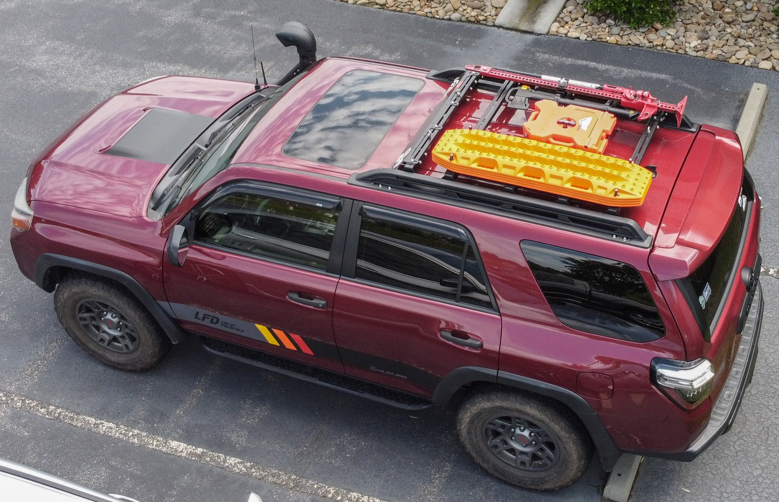 A red 2010-2013 4Runner Trail with a ruggedized crossbar installed on the roof for carrying cargo.