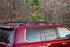 Ruggedized Crossbars mounted on the roof rails of a red 200 Series Land Cruiser vehicle, set against a forest backdrop.