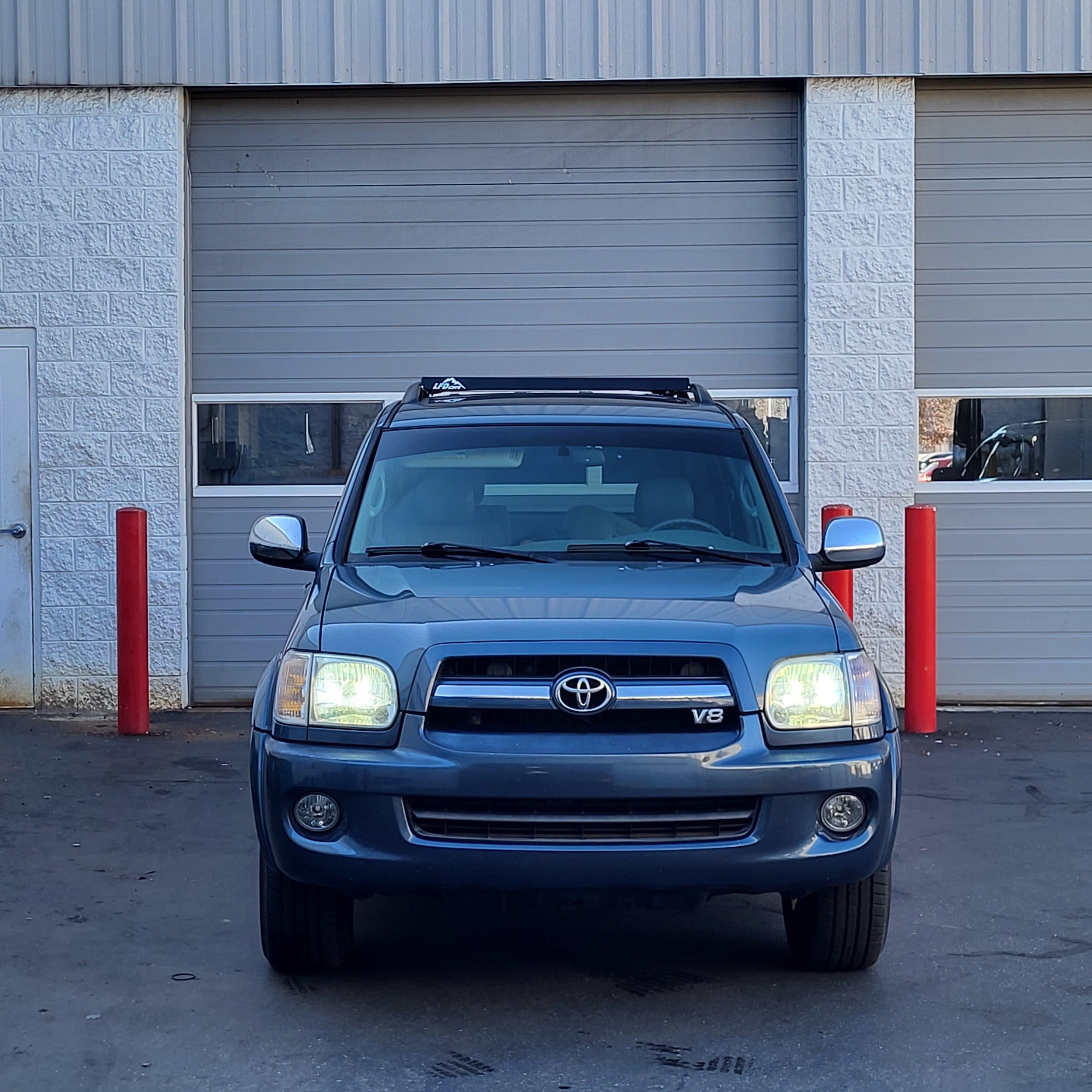A blue Toyota Sequoia with the front end visible, showing the vehicle's grille and headlights, with no visible roof cargo.