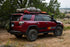 A red SUV with a roof rack that includes an angled Hi-Lift mount, allowing a Hi-Lift jack to be mounted on the side of the rack.