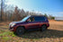A red Land Cruiser 200 SUV with a full stainless steel roof rack installed on top.