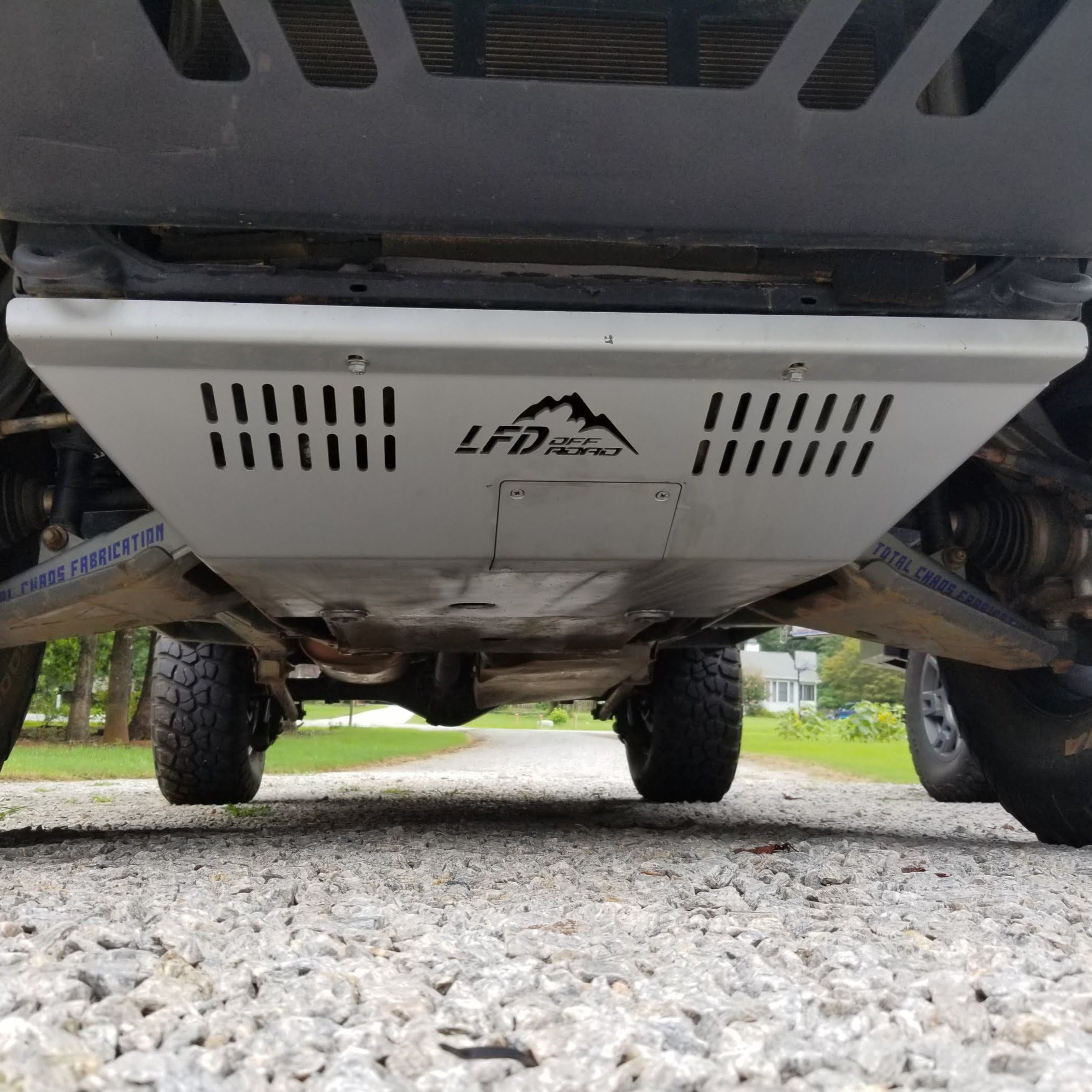 A front skid plate on a 5th Gen 4Runner, constructed of metal and featuring a Welded backing plate with countersunk holes for bolts, positioned under the vehicle's front bumper.