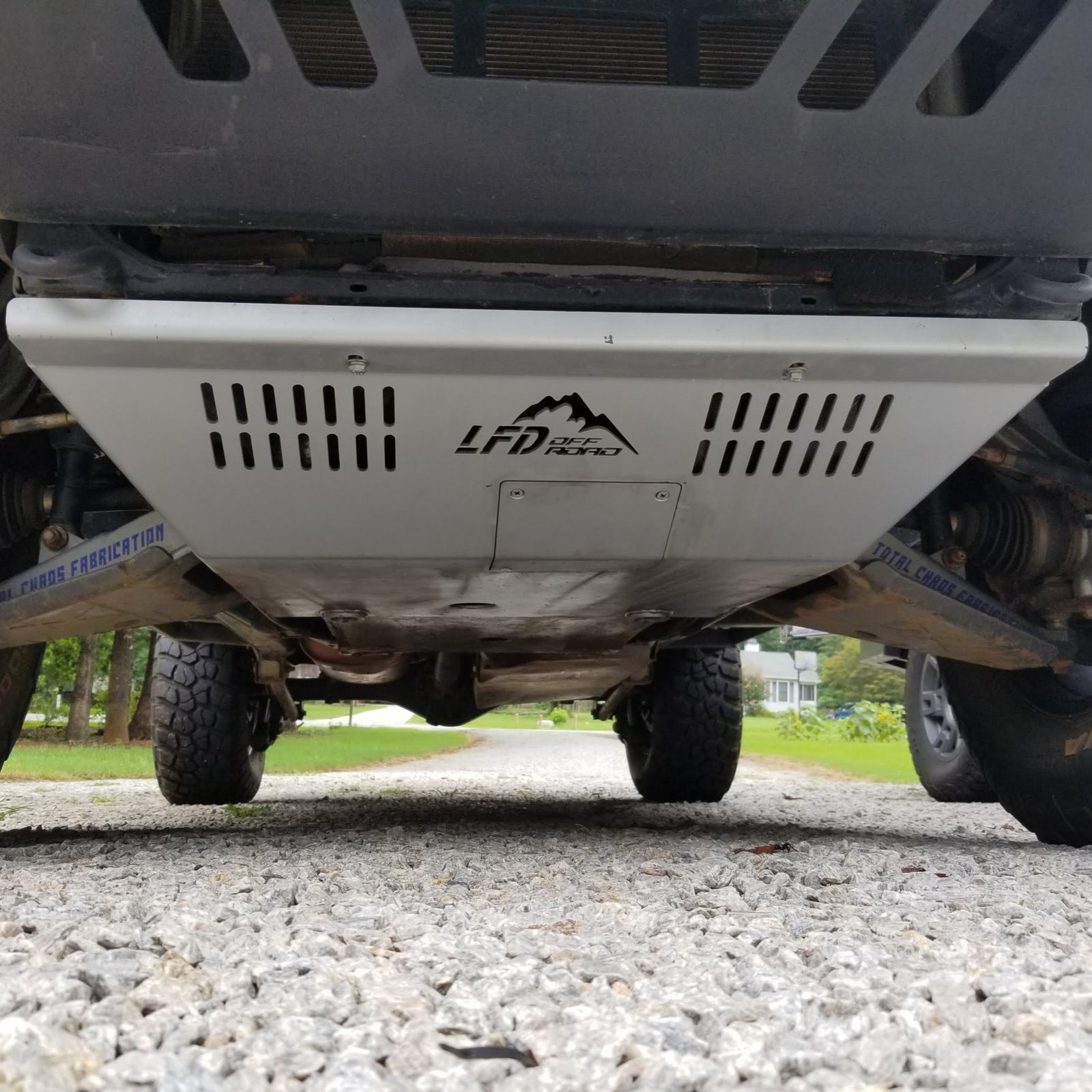 A front skid plate on a 5th Gen 4Runner, constructed of metal and featuring a Welded backing plate with countersunk holes for bolts, positioned under the vehicle's front bumper.