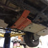 A red transfer skid plate installed underneath the rear section of a vehicle, in this case a 5th Gen 4Runner.