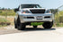 A silver Lexus GX470 with a green front skid plate installed on the vehicle, positioned on a road with a natural landscape in the background.
