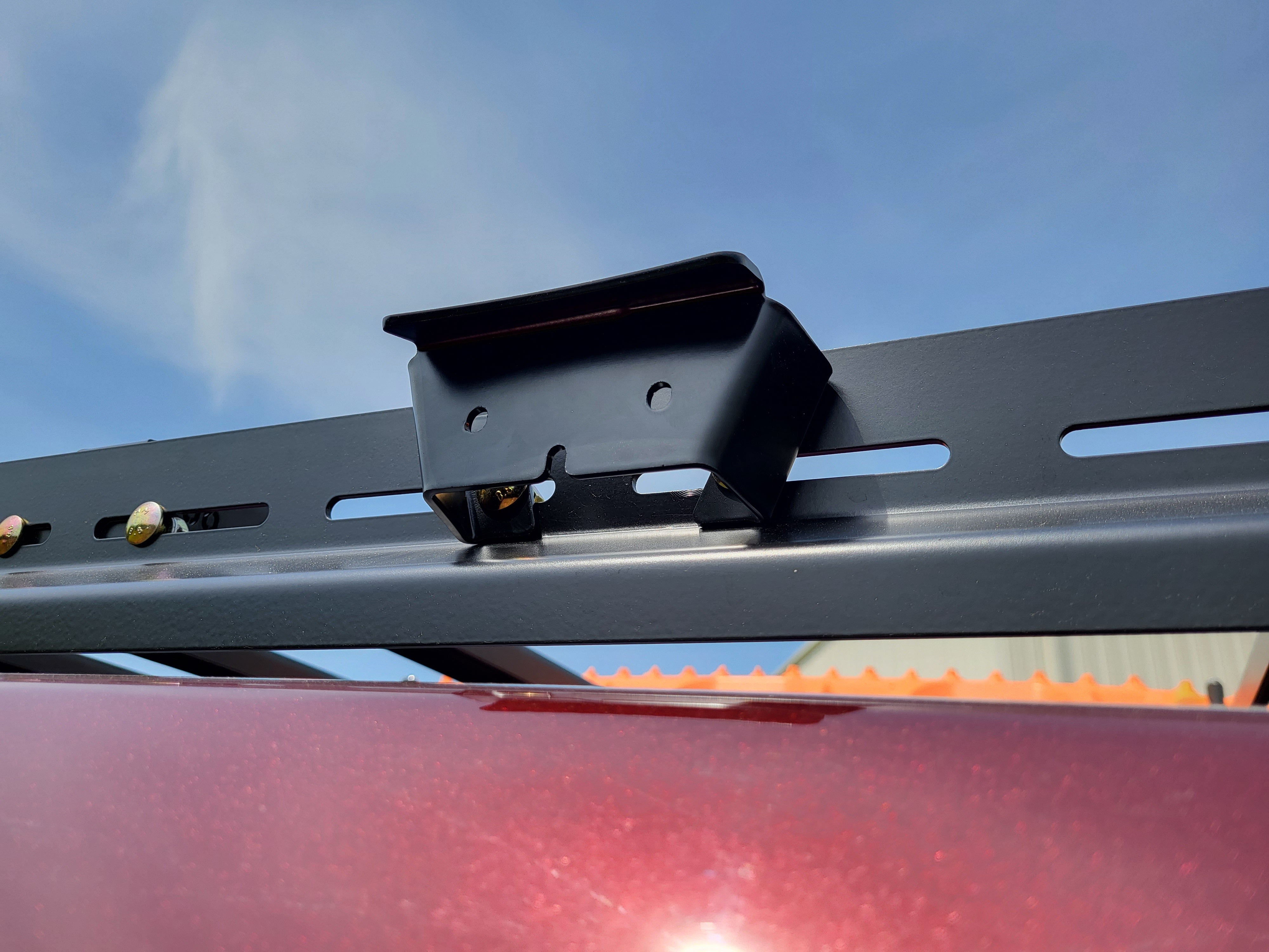 A pair of black powder-coated grab handles mounted on a vehicle roof rack, with cutouts for side lighting.