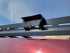 A pair of black powder-coated grab handles mounted on a vehicle roof rack, with cutouts for side lighting.
