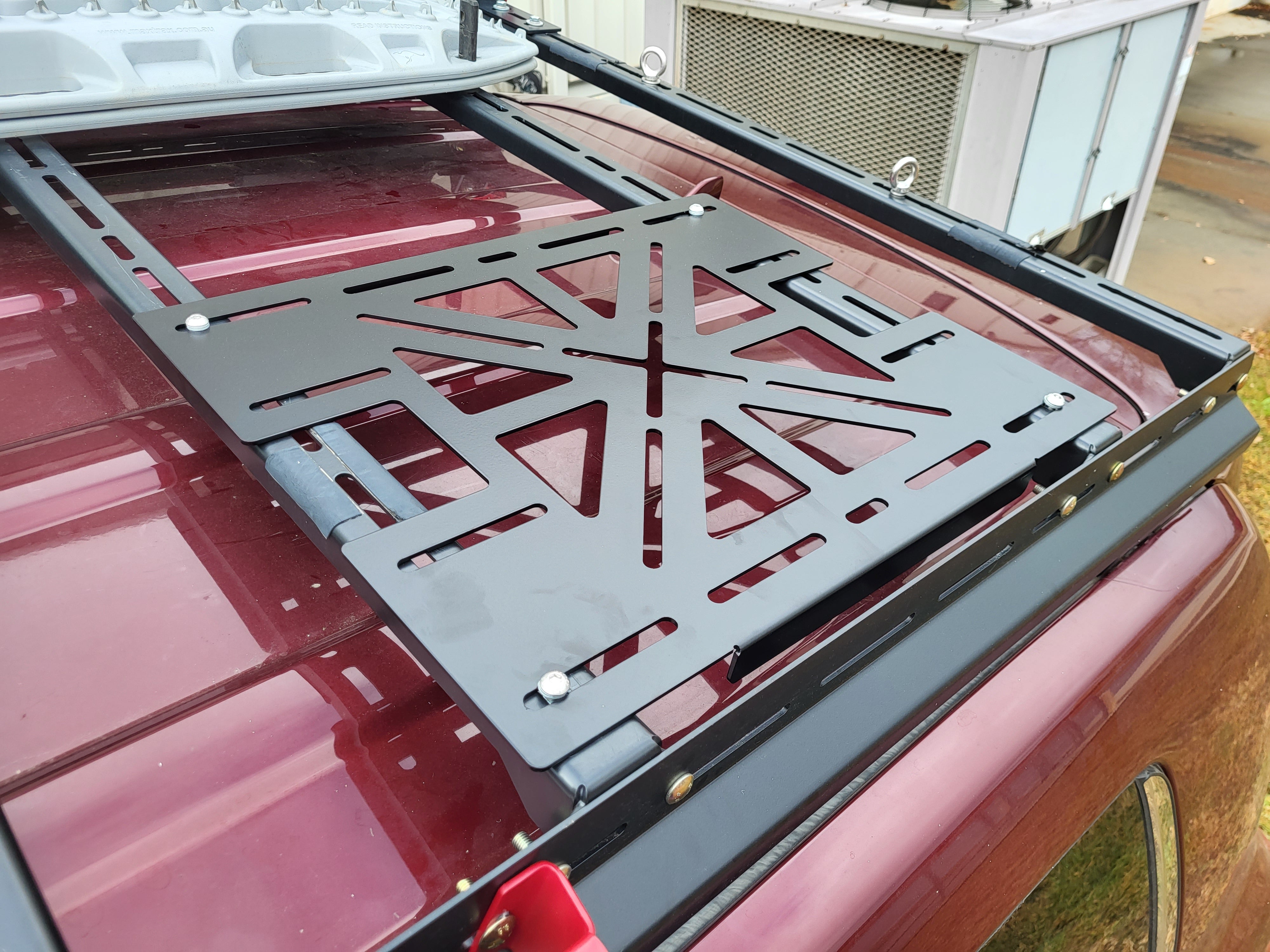 A black steel load panel mounted on a vehicle roof rack, designed to hold equipment such as FrontRunner Wolfpack cases.