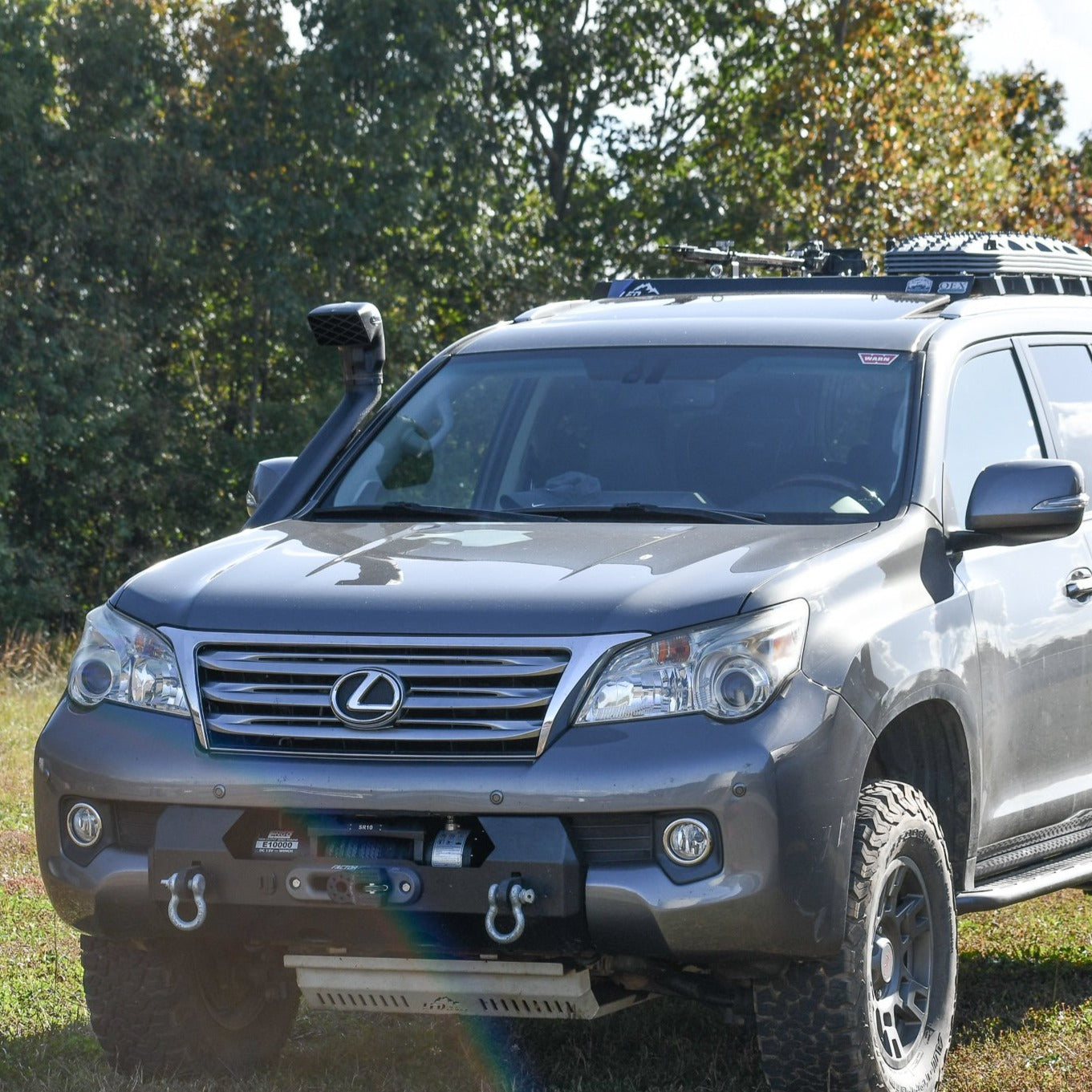 A black hybrid front bumper installed on a Lexus GX460 SUV, featuring recovery points and a winch mount.
