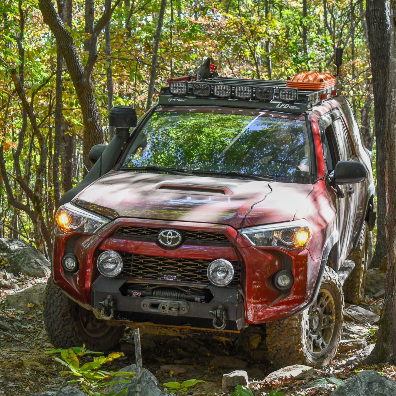 A black hybrid front bumper on a red Toyota 4Runner SUV, featuring a winch mount and recovery points.