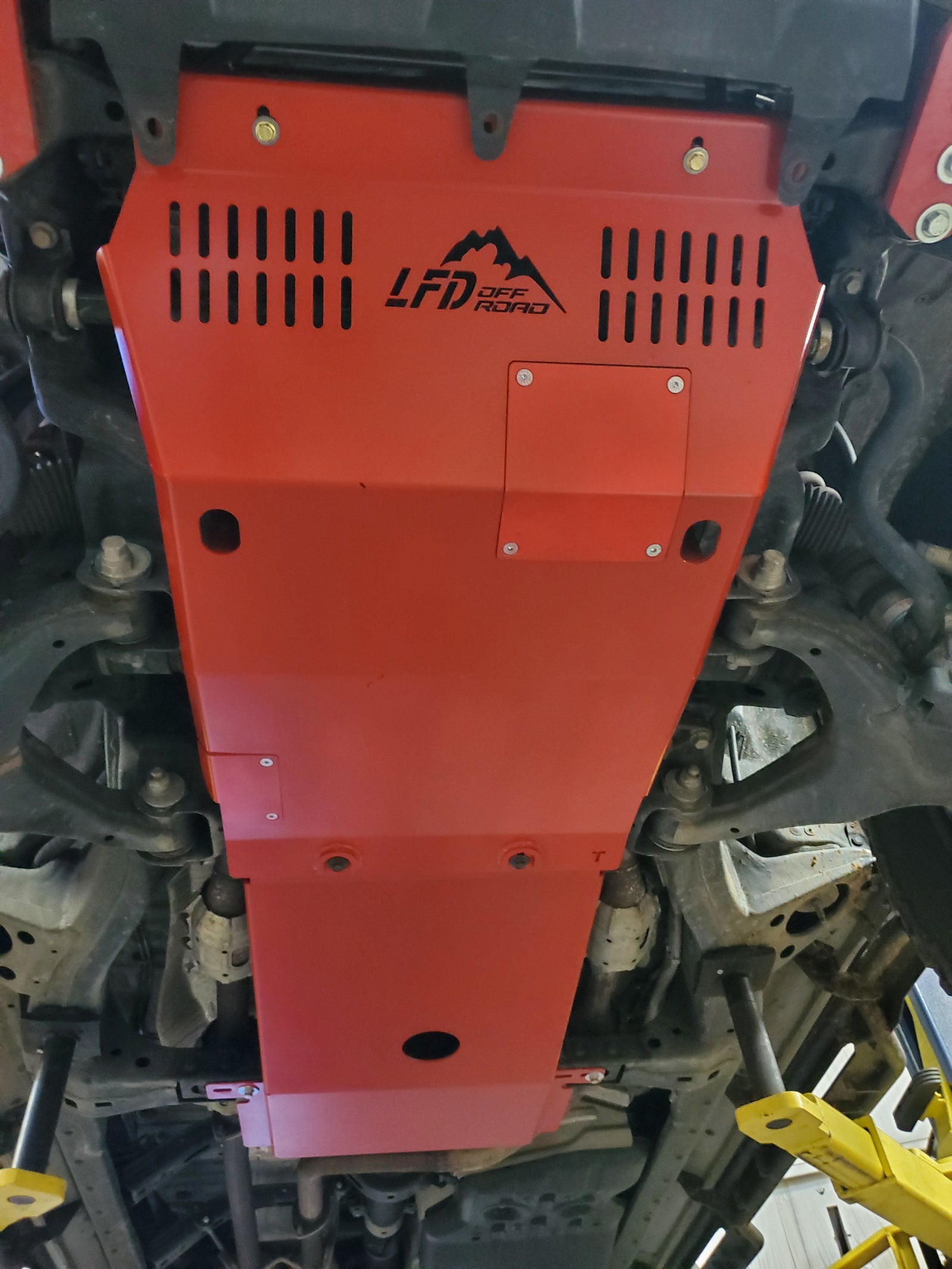Red transmission skid plate for 2nd Gen Tundra installed underneath the vehicle showcasing the product's location and fit.
