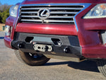 A red Lexus LX570 with the new front bumper installed, featuring a winch and recovery points, positioned in a natural outdoor setting.